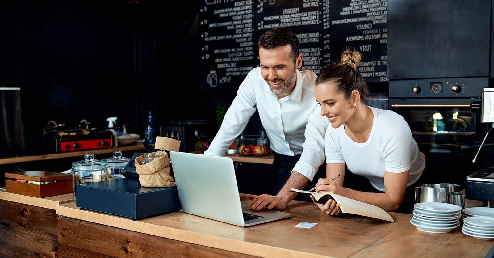 manager of a coffee shop presenting something on a laptop to his staff 